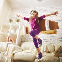 Una niña saltando en el sillón de su sala.