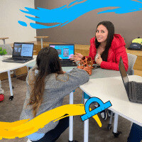 Dos jóvenes estudiando en su salón de clases, en su computador portátil.