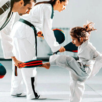 Un niño practicando taekwondo con sus maestros