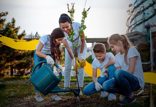 Niños con su maestra, regando una planta en el patio de su colegio