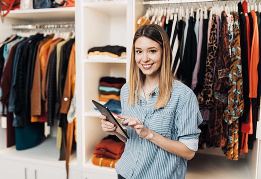 Una mujer feliz atendiendo su nueva tienda de ropa